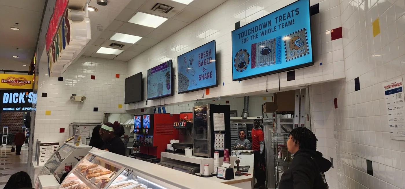 Multiple commercial television display screens mounted above a counter
